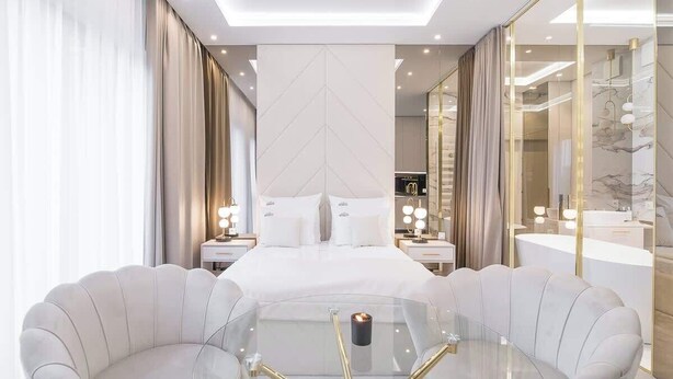 Ein modernes Schlafzimmer mit einem großen Bett, einem Glastisch und einer Wand mit Spiegeln.