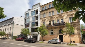 Un immeuble à plusieurs étages doté d’une façade moderne en verre et d’une façade traditionnelle en pierre.