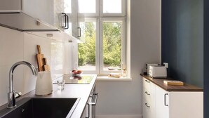 Une cuisine moderne dotée d’une fenêtre, d’appareils électroménagers en acier inoxydable et de meubles de rangement blancs.