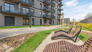 A multi-story residential building with balconies, a paved walkway, and outdoor seating. - Nadmotławie 5 | Riverside | Sauna & Gym (Gdańsk)