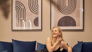 A person sitting on a dark blue sofa with a book and a fruit bowl on a side table. - Granaria B201 | Best Location (Gdańsk)