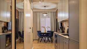 A modern kitchen with a dining area, wooden flooring, and a large window with curtains. - Granaria B201 | Best Location (Gdańsk)