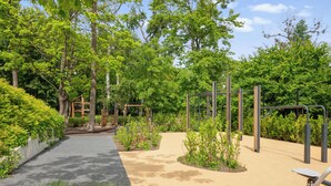 An outdoor fitness area with exercise equipment, a paved walkway, and surrounding greenery. - Nowe Kolibki 23 | 2 Bedrooms | Parking (Gdynia)