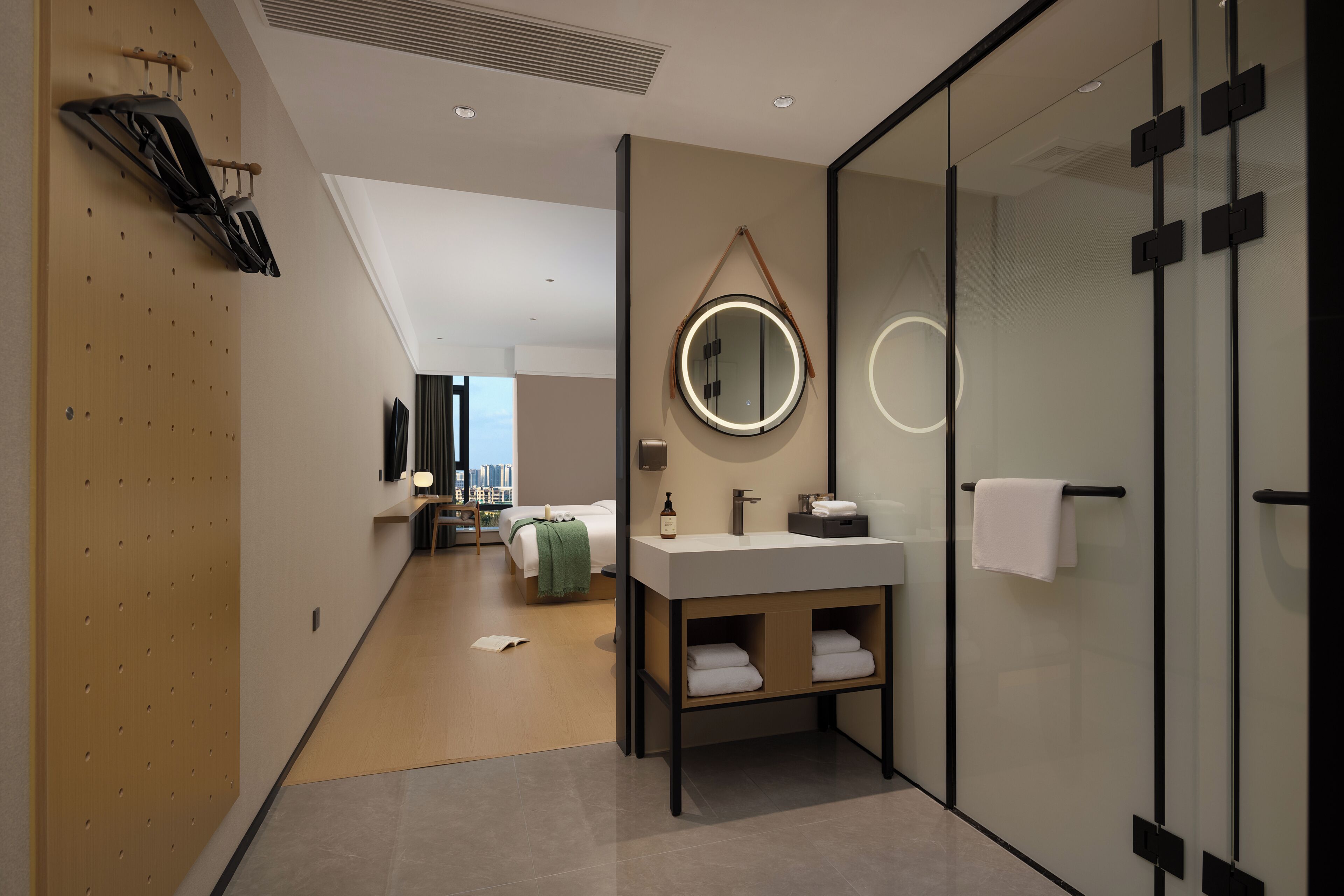 Une salle de bain d’hôtel moderne, dotée d’un grand miroir, d’un lavabo et d’un espace douche.