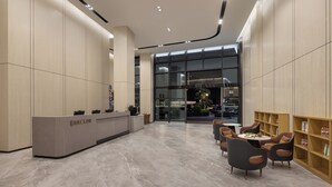 Un espace d’accueil moderne comprenant un comptoir de réception, un coin salon et une grande fenêtre.