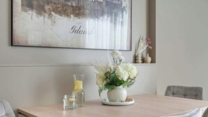 Et spisebord med en vase blomster, et glas vand og en vandflaske.