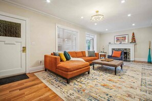 A living room with a sectional sofa, a coffee table, and a fireplace. - Spacious 4-bedroom Single Family home in Historic  Weequahic Newark NJ (Newark)
