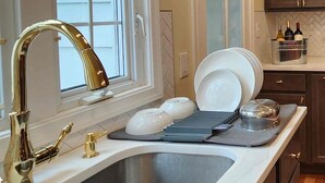 A kitchen with a stainless steel sink, a gold faucet, and a window with white blinds. - Spacious 4-bedroom Single Family home in Historic  Weequahic Newark NJ (Newark)