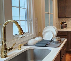 A kitchen with a stainless steel sink, a gold faucet, and a window with white blinds. - Spacious 4-bedroom Single Family home in Historic  Weequahic Newark NJ (Newark)