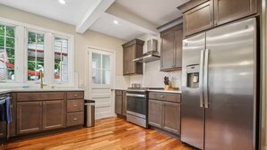 A modern kitchen with stainless steel appliances, wooden flooring, and a view of the outdoors. - Spacious 4-bedroom Single Family home in Historic  Weequahic Newark NJ (Newark)
