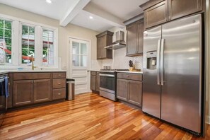 A modern kitchen with stainless steel appliances, wooden flooring, and a view of the outdoors. - Spacious 4-bedroom Single Family home in Historic  Weequahic Newark NJ (Newark)