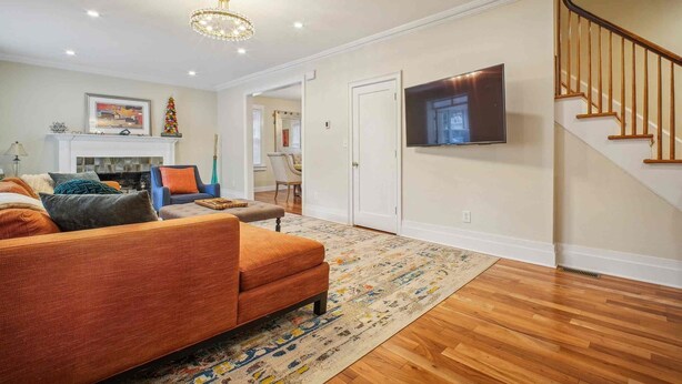 A living room with a sofa, a fireplace, a television, and a staircase. - Spacious 4-bedroom Single Family home in Historic  Weequahic Newark NJ (Newark)