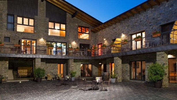 A multi-story building with stone walls, balconies, and outdoor seating areas.
