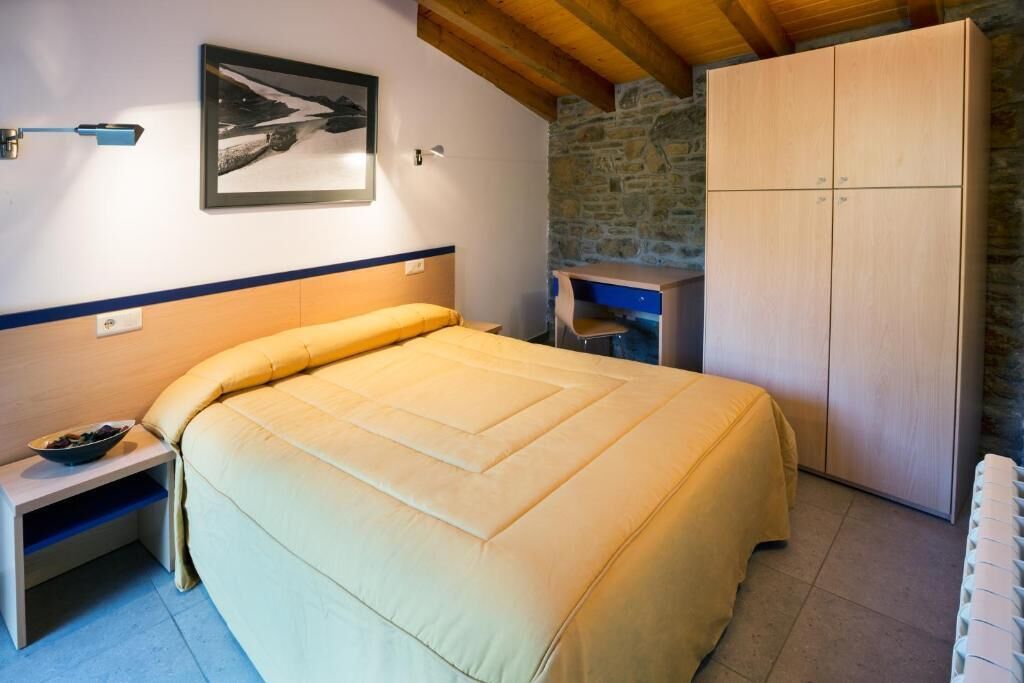 Een slaapkamer met een bed, nachtkastje, bureau en een kledingkast.