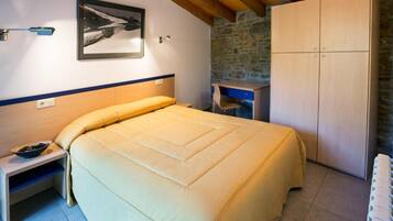 Een slaapkamer met een bed, nachtkastje, bureau en een kledingkast.