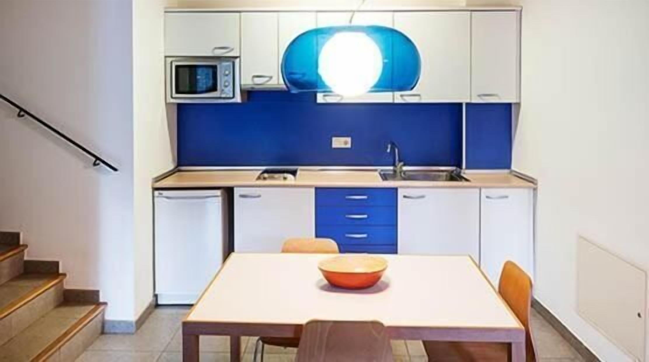 Een kleine keuken met een magnetron, wastafel en een tafel met een kom.
