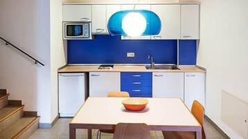 Een kleine keuken met een magnetron, wastafel en een tafel met een kom.