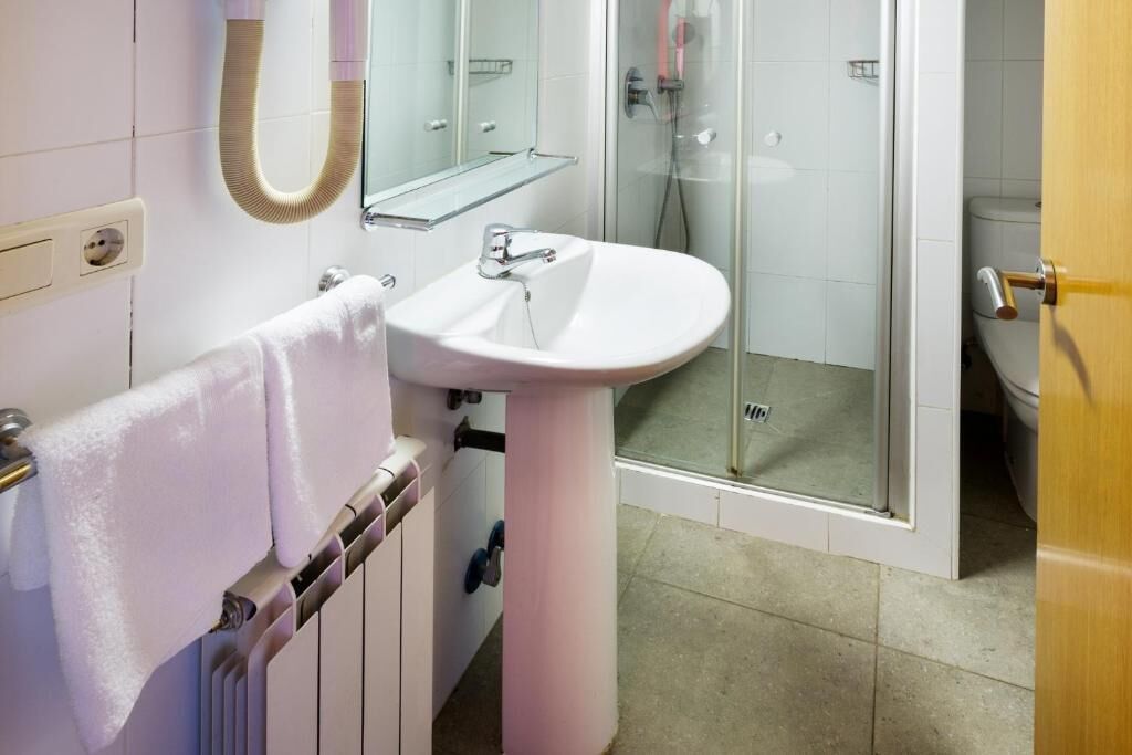 A bathroom with a white sink, a glass shower enclosure, and a towel rack.