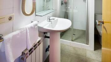 A bathroom with a white sink, a glass shower enclosure, and a towel rack.