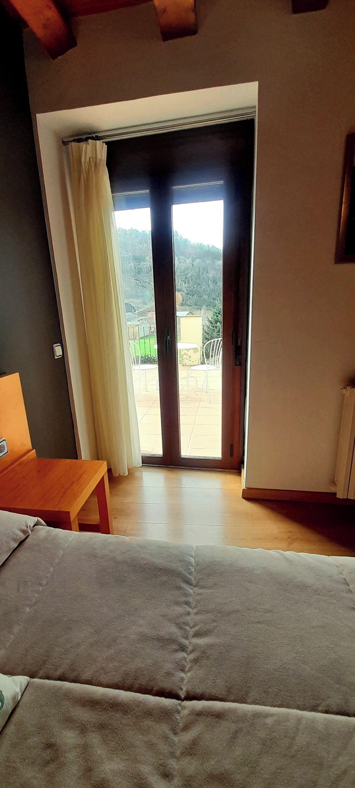Una habitación con sofá, una mesa de madera y un ventanal corredero que da a un patio exterior.