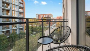 Un balcón con vistas a un paisaje urbano, una silla y una mesita.