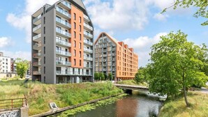 Un moderno edificio de apartamentos con balcones, un río y un puente.