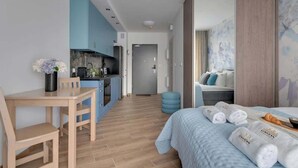Une chambre d’hôtel moderne équipée d’une kitchenette, d’un coin repas et d’un lit avec des serviettes.