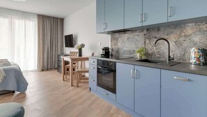 Une cuisine moderne avec des meubles de couleur bleu clair, un pare-feu en marbre et un four encastré.