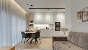 Een moderne woonkamer met een bank, een salontafel en een eethoek met stoelen en een tafel.
