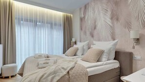 Een moderne hotelkamer met een groot bed, een nachtkastje, een lamp en een muur met een palmbladpatroon.