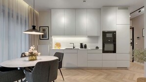 Een moderne keuken met witte kastjes, een centraal eiland en een eethoek met een ronde tafel en stoelen.