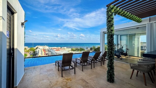 Ein Balkon mit Pool, Sitzgelegenheiten im Freien und Blick aufs Meer.