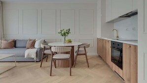 Een moderne keuken met witte kasten, een ronde eettafel met stoelen en een ingebouwde oven.