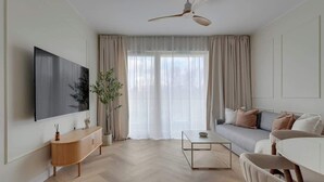 Een moderne woonkamer met een flatscreen televisie, een plafondventilator, een bank, een salontafel en een potplant.