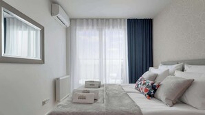 Une chambre d’hôtel avec un lit, une fenêtre avec des rideaux, un radiateur et un climatiseur fixé au mur.