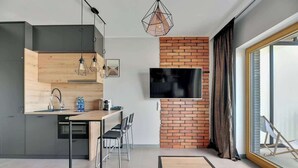 Una cocina moderna con televisor, comedor y un amplio ventanal.