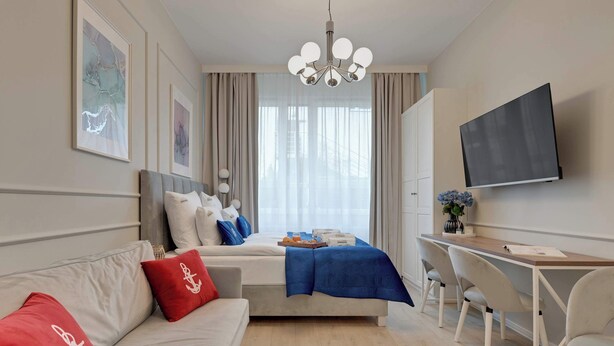 Ein modernes Hotelzimmer mit Bett, Schreibtisch, Fernseher und Bildern an den Wänden.