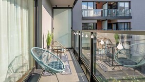 A modern balcony with glass railings, wicker chairs, and hanging light fixtures. - Nadmotławie C31 | Riverside | Sauna & Gym (Gdańsk)