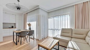 A modern living room with a sofa, dining table, chairs, and a coffee table. - Nadmotławie C31 | Riverside | Sauna & Gym (Gdańsk)