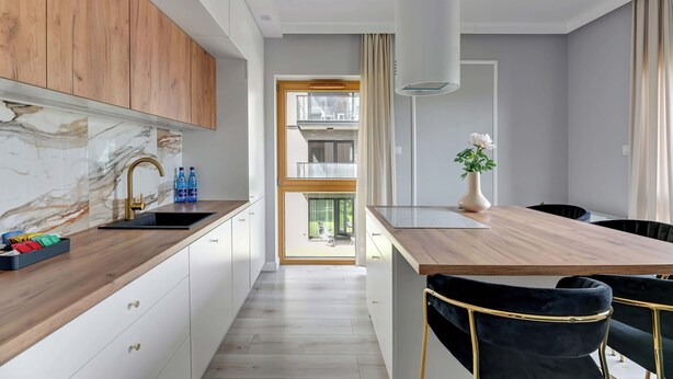 Una cucina moderna con piano di lavoro in legno, un lavello e zona pranzo con tavolo e sedie.