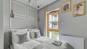 Una camera da letto con un letto grande, due comodini, una finestra vista edificio e un termosifone.
