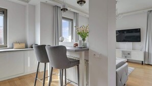 Une cuisine moderne dotée d’un coin bar, d’une table à manger et d’un téléviseur fixé au mur.