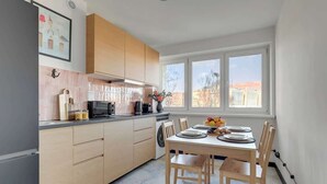 Een moderne keuken met houten keukenkastjes, een eettafel gedekt voor vier personen en een groot raam met uitzicht op de stad.