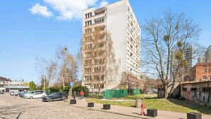 Een meerlaags gebouw met balkons, een parkeerplaats en een voetpad.