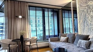 Un salon moderne avec un canapé, une table ronde et une petite table d’appoint.