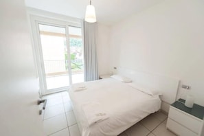 Ein Hotelzimmer mit einem Bett, einem Nachttisch, einem Fenster mit Vorhängen und Blick nach draußen.
