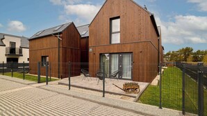 A modern wooden building with a large window, a wheelchair-accessible outdoor seating area, and a paved entrance. - Sunset Wood Resort 4 | Jacuzzi | Parking (Jastrzębia Góra)