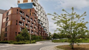 Un edifici modern de diverses plantes amb un disseny arquitectònic singular, caracteritzat per una combinació de façanes de maó i vidre.