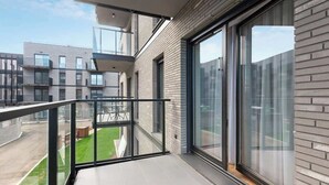Um apartamento moderno com varanda, janelas amplas e vista para outros edifícios.