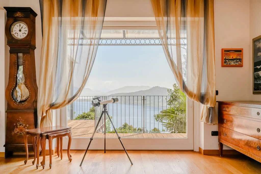 A room with a balcony, a telescope, a clock, and a dresser.